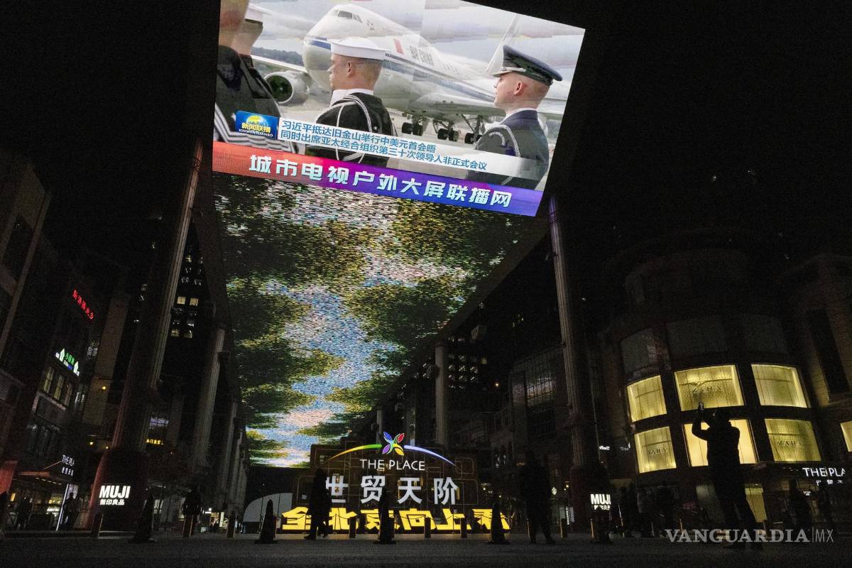 $!Un hombre (d) toma una fotografía de una gran pantalla que muestra la llegada del presidente chino Xi Jinping a Estados Unidos, en un centro comercial de Beijing.