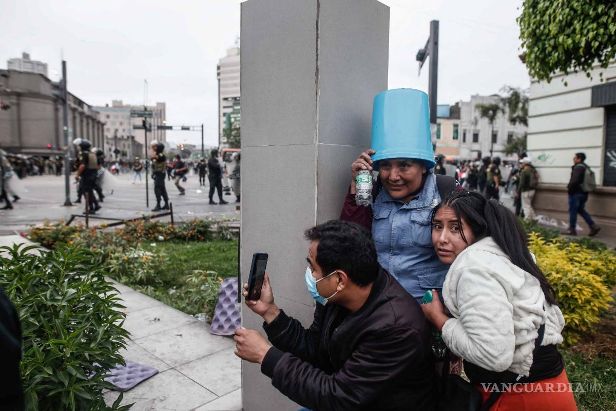 $!Un grupo de personas se resguarda durante los enfrentamientos entre manifestantes y la Policía a las afueras de la Prefectura de Lima.