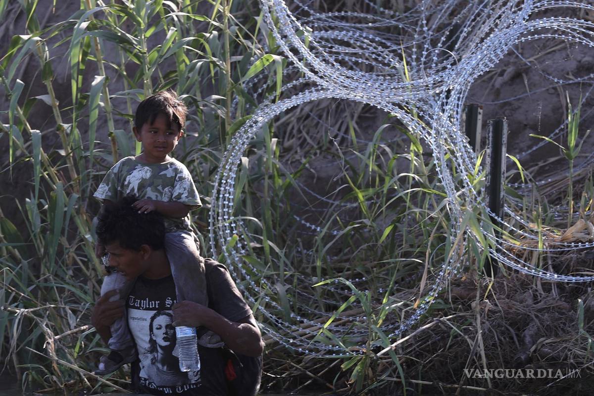 $!Un migrante con un niño camina a lo largo del Río Grande en Eagle Pass, Texas.