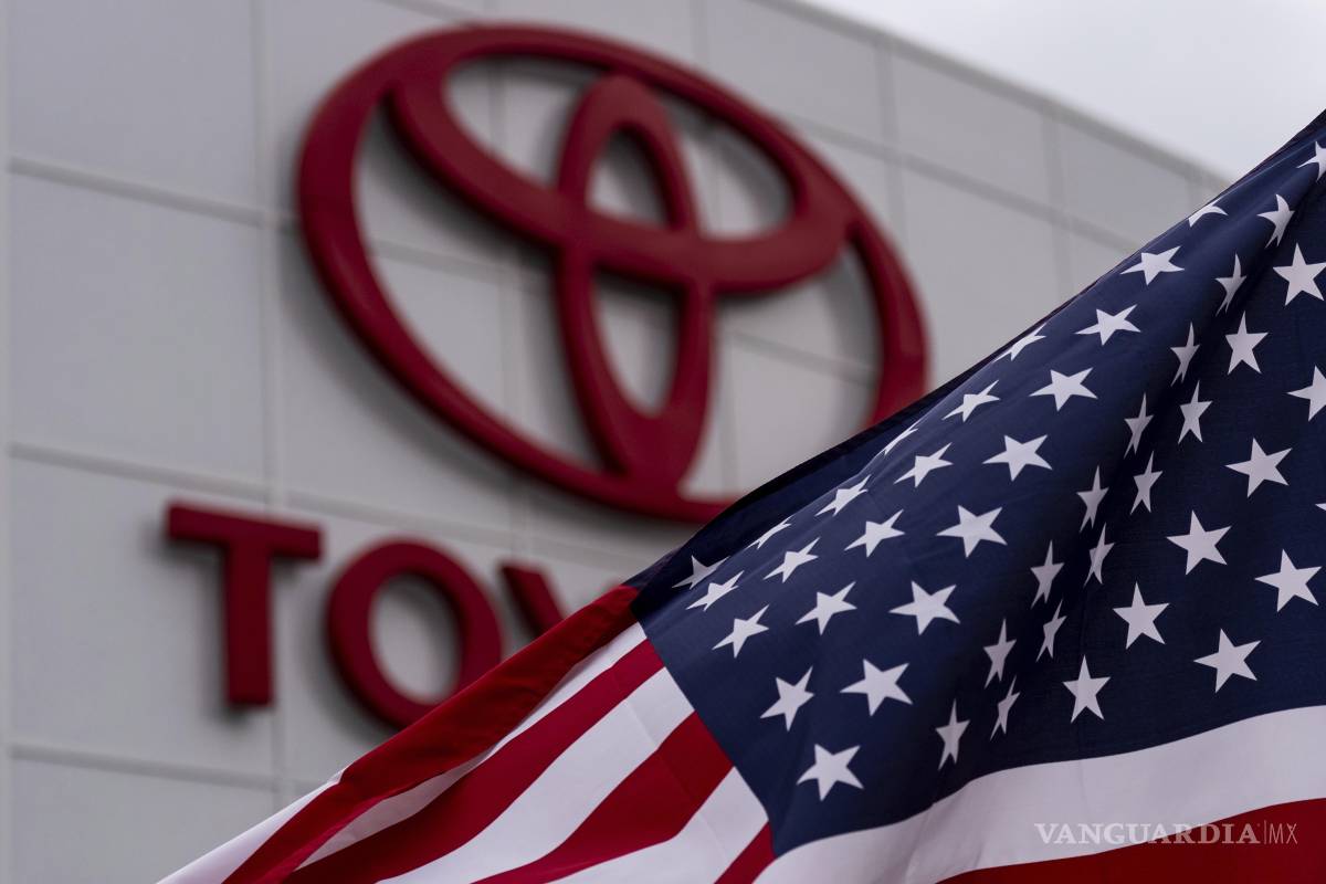 $!Una bandera estadounidense ondea al viento frente al logotipo de Toyota en un concesionario de Cerritos, California.