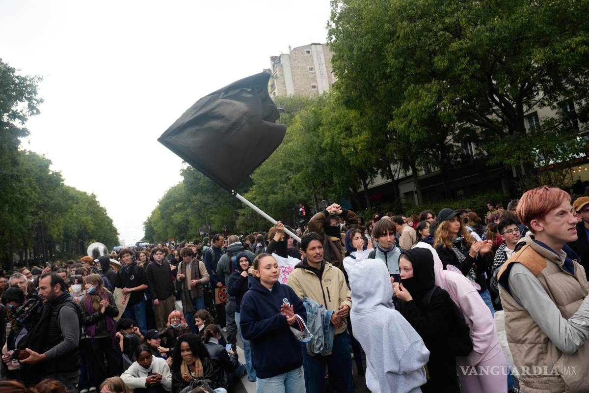 $!Manifestantes ondean una bandera mientras se reúnen en París, el jueves 22 de octubre de 2026, para protestar contra las deficientes condiciones escolares.