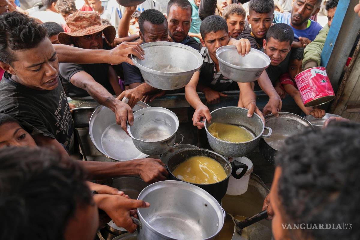$!Palestinos tratan de conseguir comida cocinada de una cocina comunitaria en Jan Yunis, en el sur de la Franja de Gaza.