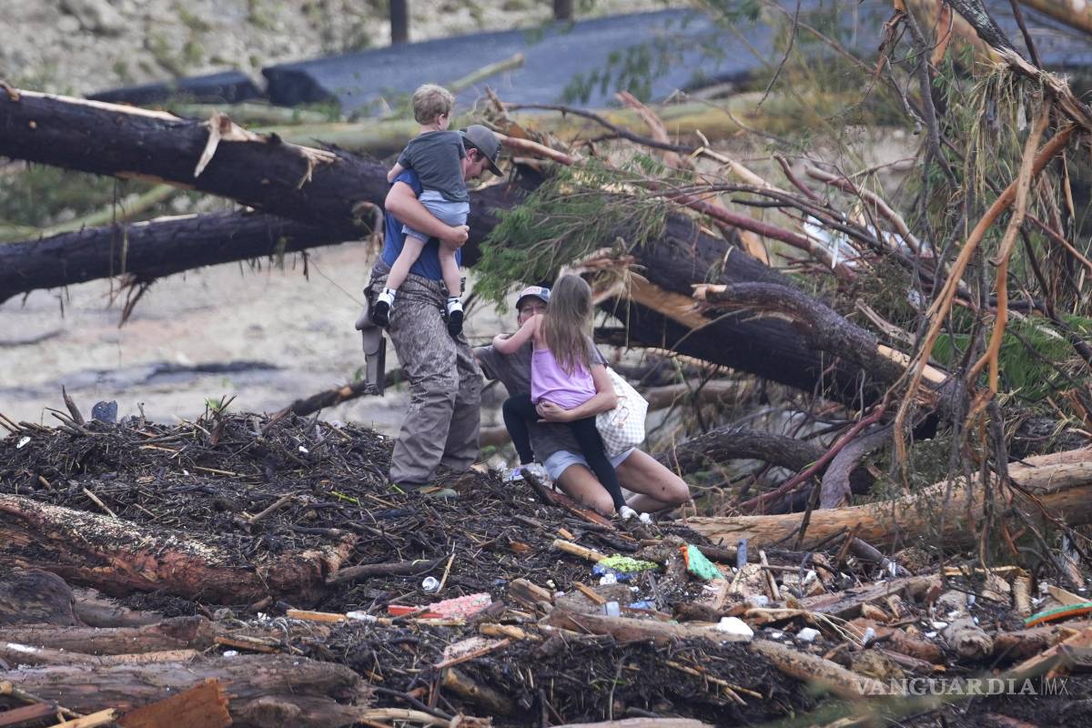 $!Una mujer cae mientras camina entre escombros en un puente sobre el río Guadalupe luego de que una inundación repentina azotó la zona.