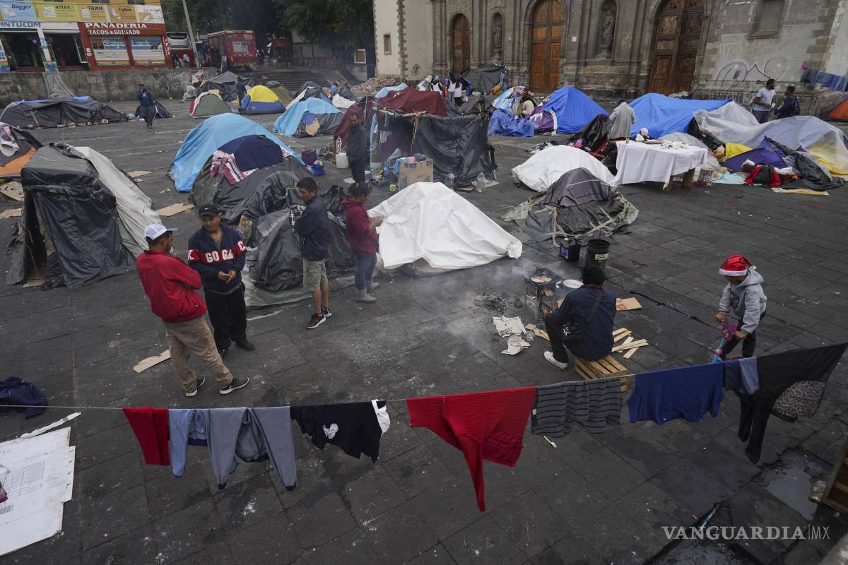 $!Migrantes se reúnen en un campamento instalado en la plaza de la parroquia de Santa Cruz y La Soledad en el barrio de La Merced de Ciudad de México.