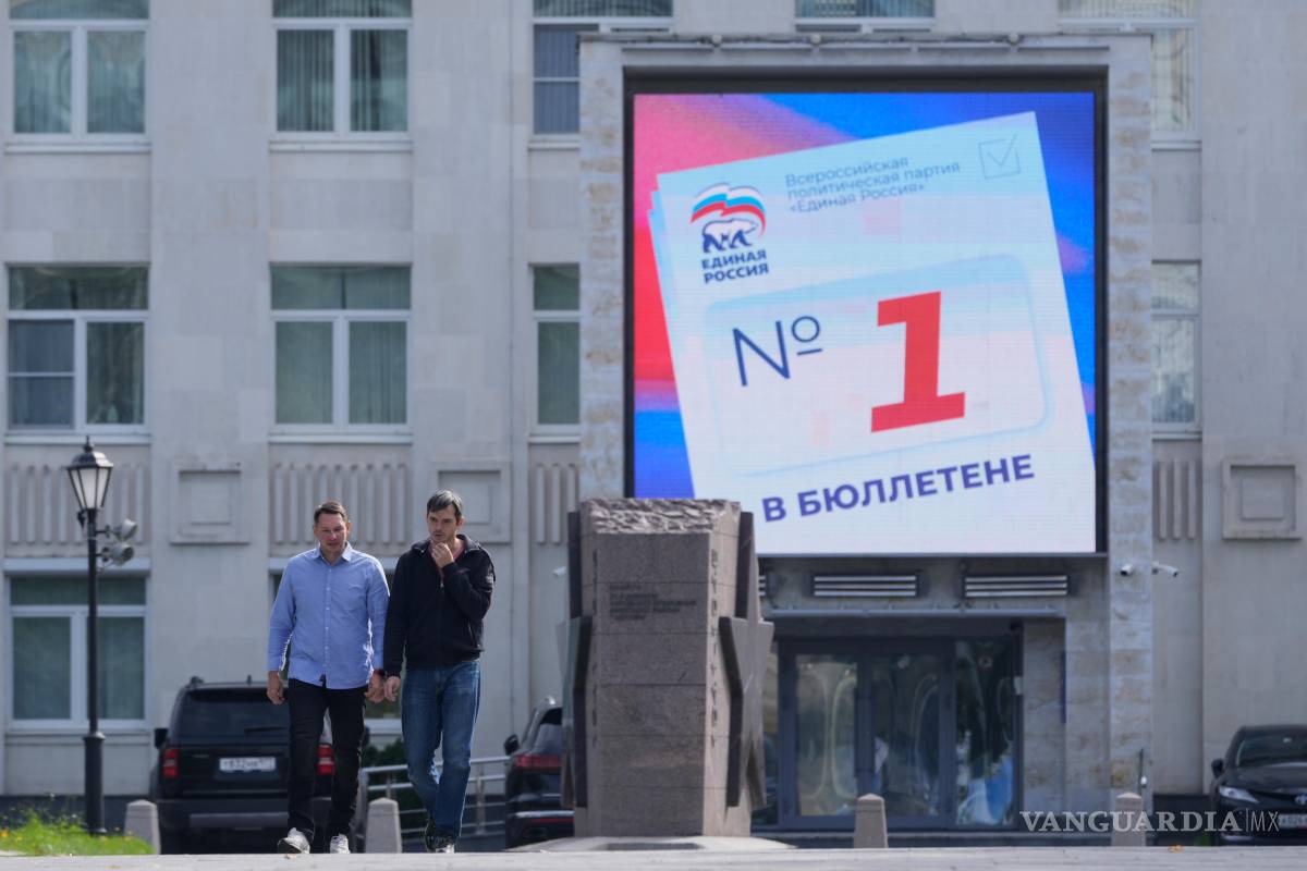 $!Unas personas pasan frente a una valla publicitaria digital en Moscú que promociona al partido Rusia Unida de cara a las elecciones parlamentarias.