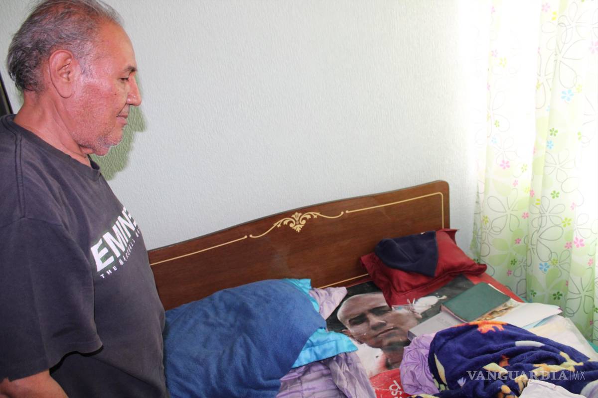 $!Óscar Flores, padre de Jesús Daniel Flores García, a un costado de la cama donde duerme siempre con la lona que lleva el rostro de su hijo. Siempre antes de dormir, besa la lona