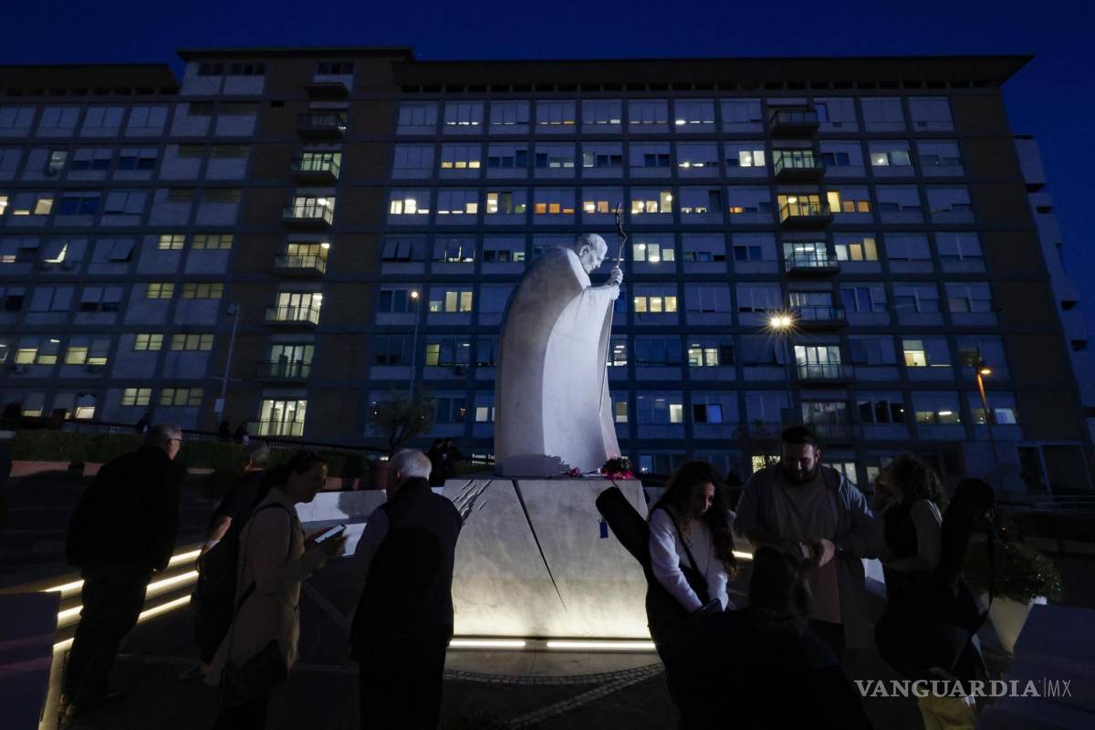 $!Personas rezan frente a la estatua del papa Juan Pablo II en el exterior del Hospital Universitario Agostino Gemelli, donde está hospitalizado el papa León XIV.