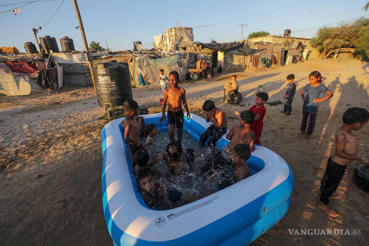 $!Niños refugiados palestinos se refrescan en una piscina inflable en un barrio marginal en las afueras del campo de refugiados de Khan Younis, Franja de Gaza.