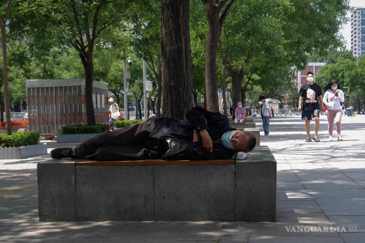 $!Un hombre usa una máscara facial mientras duerme en un banco en Beijing, China.