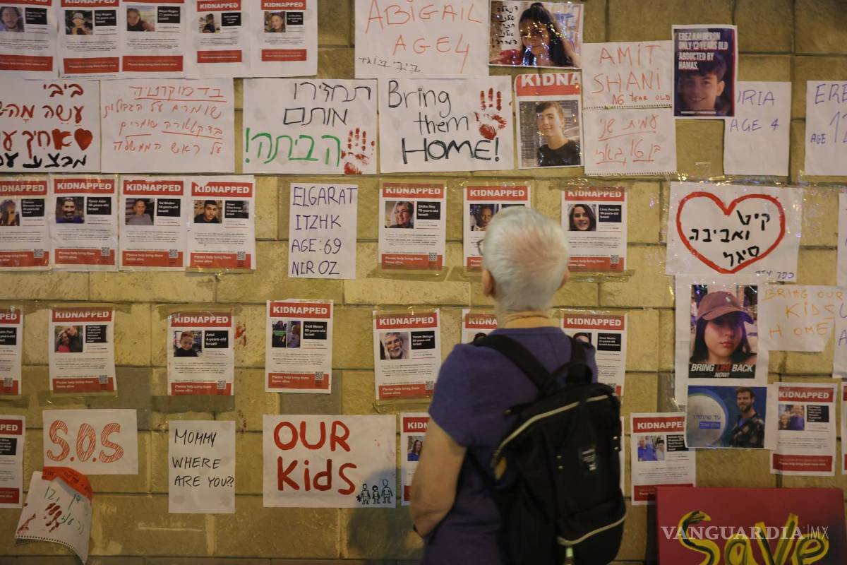 $!Una persona mira fotografías de rehenes retenidos por militantes de Hamas durante una protesta pidiendo al gobierno israelí que ayude a rescatarlos.