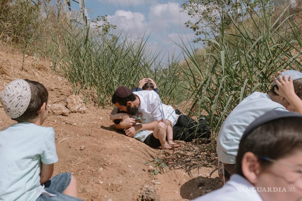 $!Gente se cubre mientras suena una sirena antiaérea para alertar de cohetes lanzados en la Franja de Gaza en Rehovot, Israel, el viernes 13 de octubre de 2023.