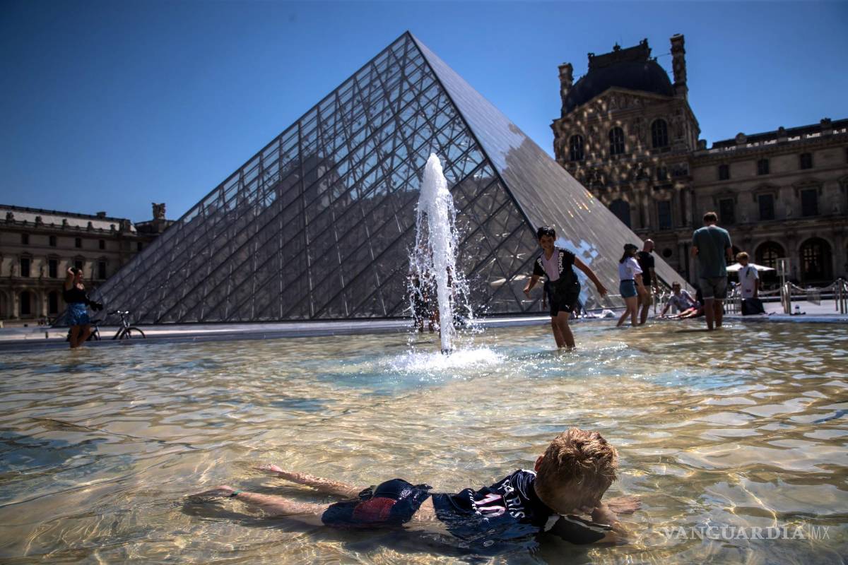 $!Parisinos y turistas se refrescan en las fuentes de la Pirámide del Museo del Louvre en París, Francia.