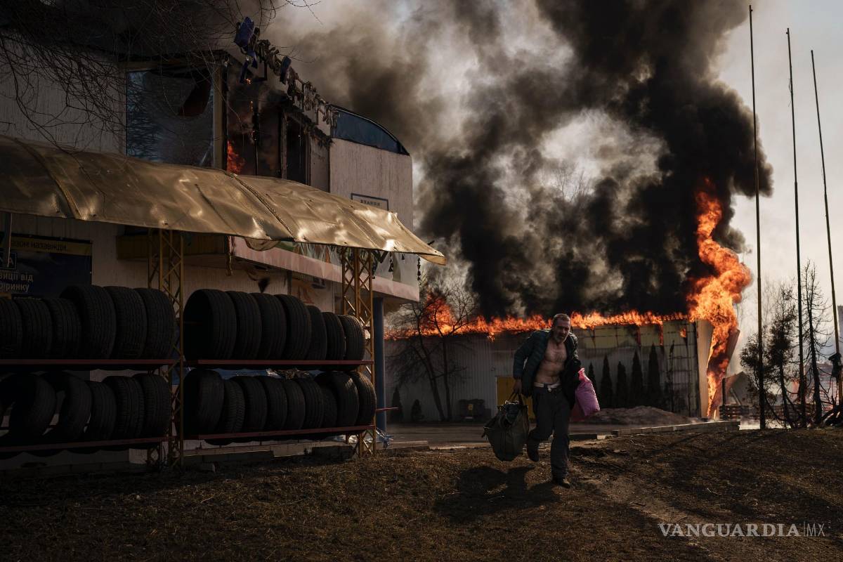 $!Un hombre corre mientras recupera artículos de una tienda en llamas tras un ataque ruso en Járkiv, Ucrania, el 25 de marzo de 2022.