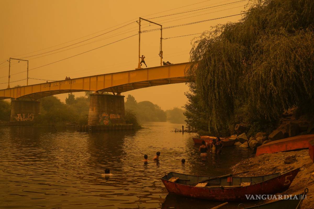 $!Varias personas nadan en el río Renaico bajo un cielo cubierto del humo causado por los incendios, en Renaico, Chile, el 4 de febrero de 2023.