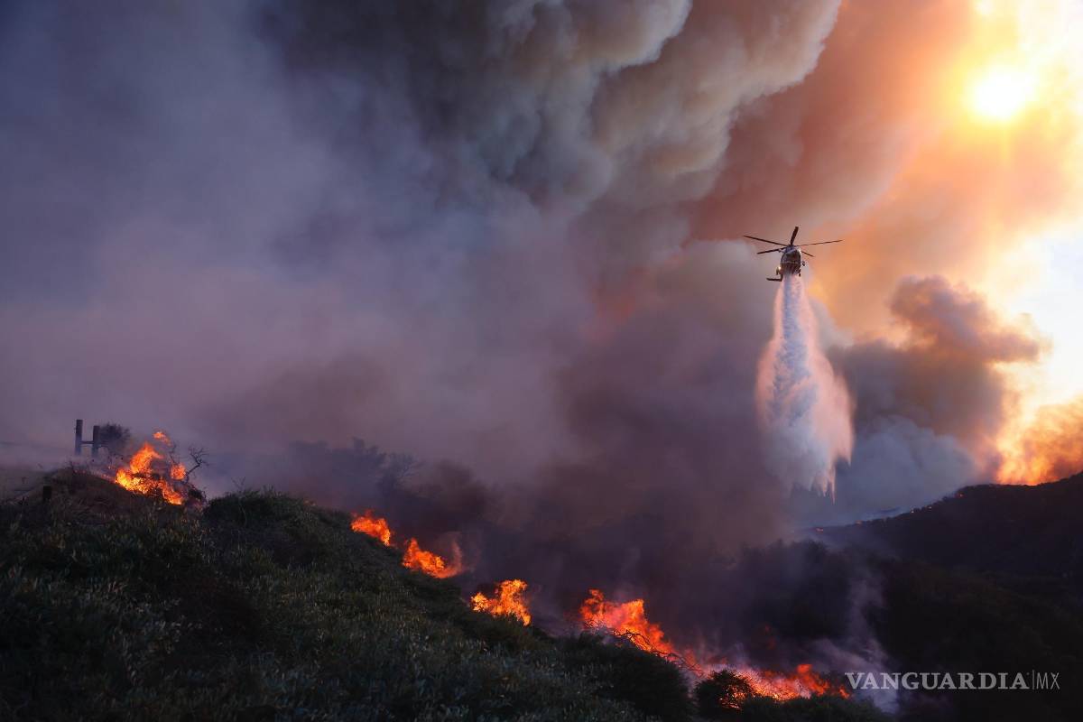 $!Un helicóptero arroja agua sobre el incendio Palisades que avanza en el vecindario Pacific Palisades de Los Ángeles, el martes 7 de enero de 2025.