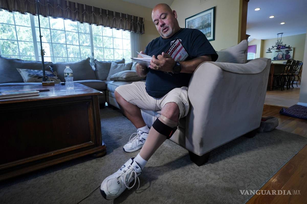 $!Will Jimeno, un ex agente de policía de la Autoridad Portuaria que fue rescatado de entre los escombros del World Trader Center el 11S, lee el libro ilustrado para niños que escribió Immigrant, American, Survivor (“Inmigrante, Estadounidense, Sobreviviente”) contando su experiencia, durante una entrevista en su casa en Chester, Nueva Jersey, el 2 de agosto de 2021. Herido en el 11S, Jimeno usa una media de compresión y un brazalete en su pierna izquierda. AP/Richard Drew