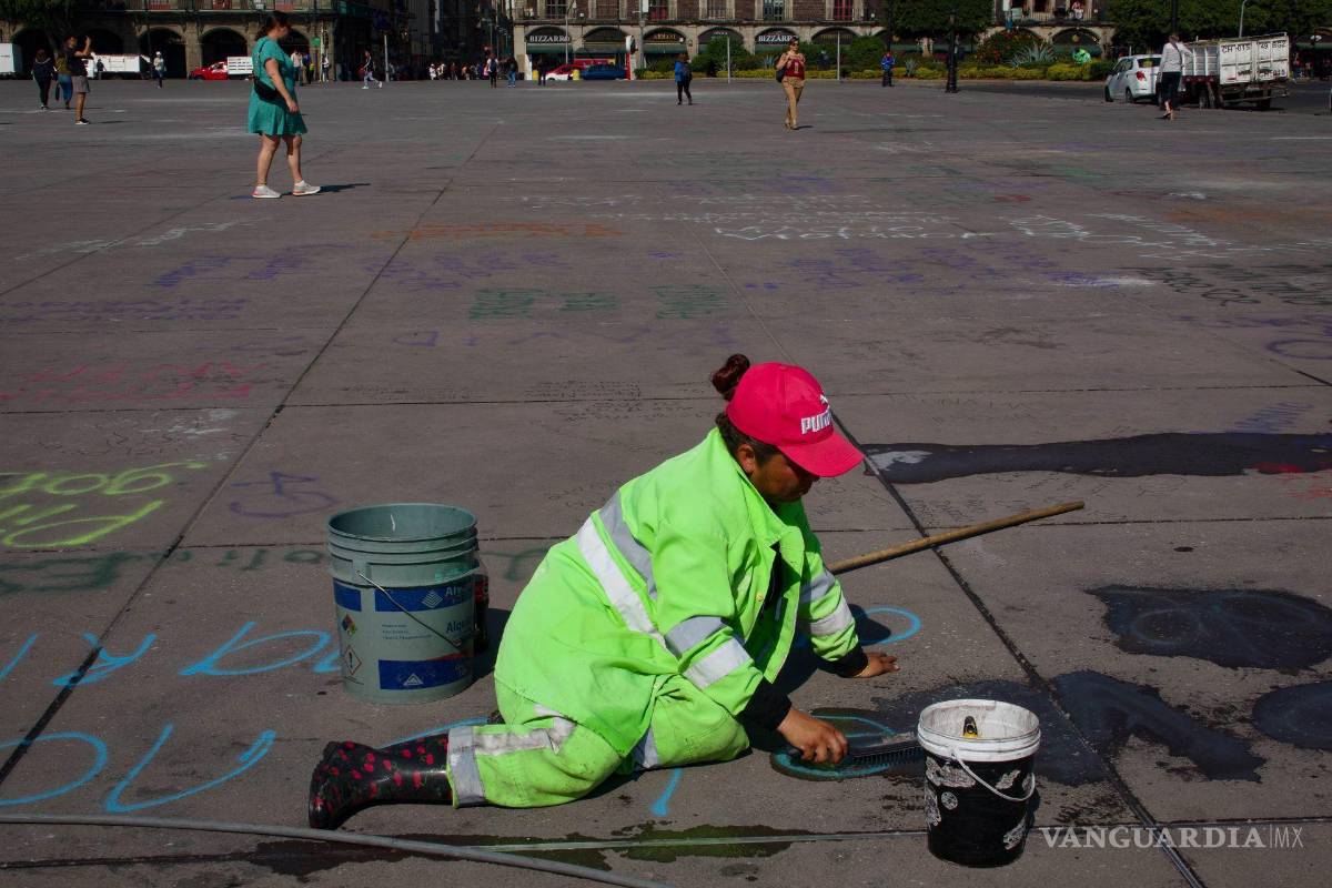 $!Una trabajadora realizan limpieza de pintas en la plancha del Zócalo en CDMX.