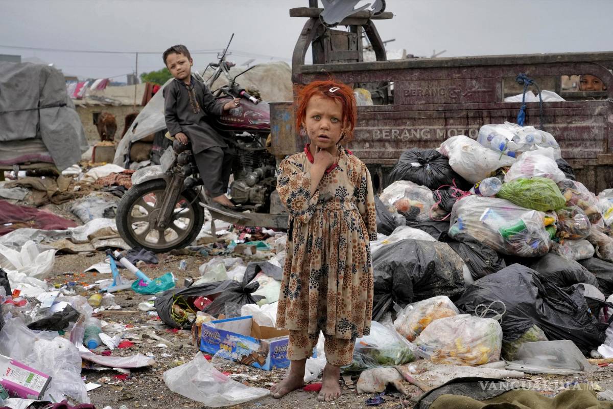 $!Dos niños afganos se paran en medio de montones de basura al lado de su casa, en Kabul, Afganistán.