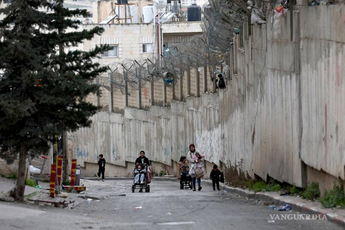 $!Mujeres palestinas caminan junto a la barrera de separación israelí en Al Ram, que divide Jerusalén de Cisjordania.