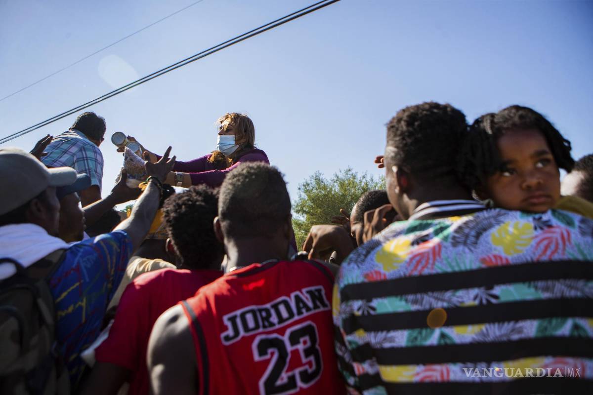 $!Araselli Zamora from San Antonio hands resources including food, clothing and baby carriers to a group of migrants early Friday, Sept. 17, 2021, in Ciudad Acuña, Mexico. Haitians crossed the Rio Grande freely and in a steady stream, going back and forth between the U.S. and Mexico through knee-deep water with some parents carrying small children on their shoulders. Unable to buy supplies in the U.S., they returned briefly to Mexico for food and cardboard to settle, temporarily at least, under or near the bridge in Del Rio, a city of 35,000 that has been severely strained by migrant flows in recent months. (Marie D. De Jesús/Houston Chronicle via AP)