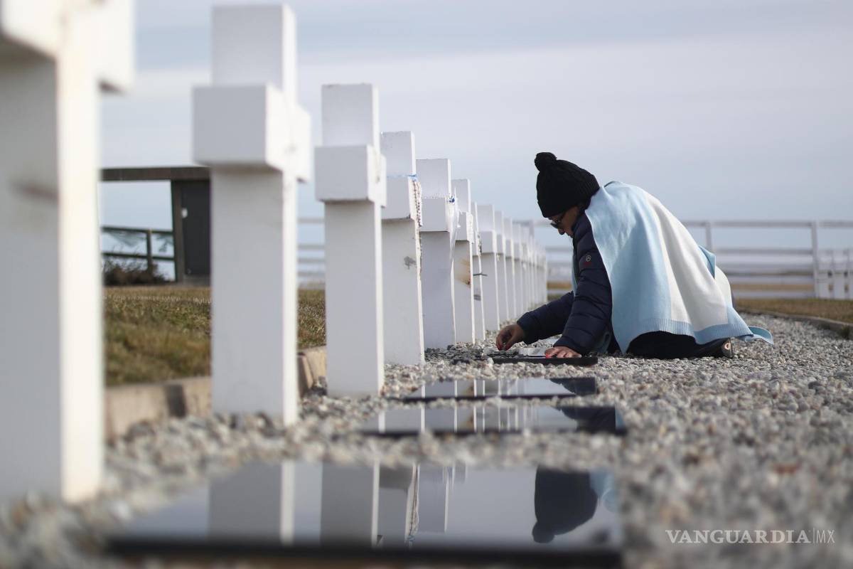 $!Una mujer con la bandera de Argentina visita una tumba este viernes, en el Cementerio Militar Argentino de Darwin, en las Islas Malvinas.