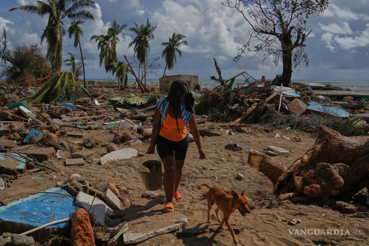 $!Una mujer y su perro caminan entre las ruinas de las casas destruidas por el huracán Melissa en Boca de dos Ríos, Cuba.