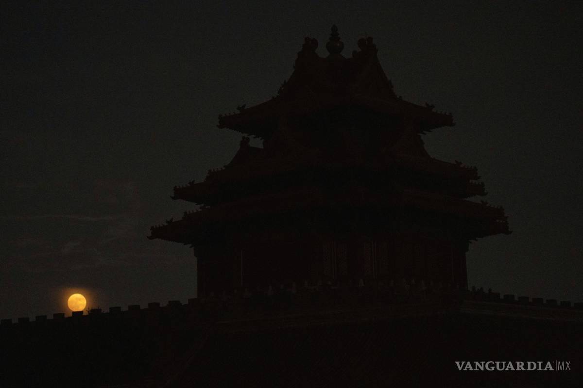 $!La torre de la esquina de la Ciudad Prohibida se recorta cerca del anochecer cuando una superluna se eleva cerca del horizonte en Beijing, China.