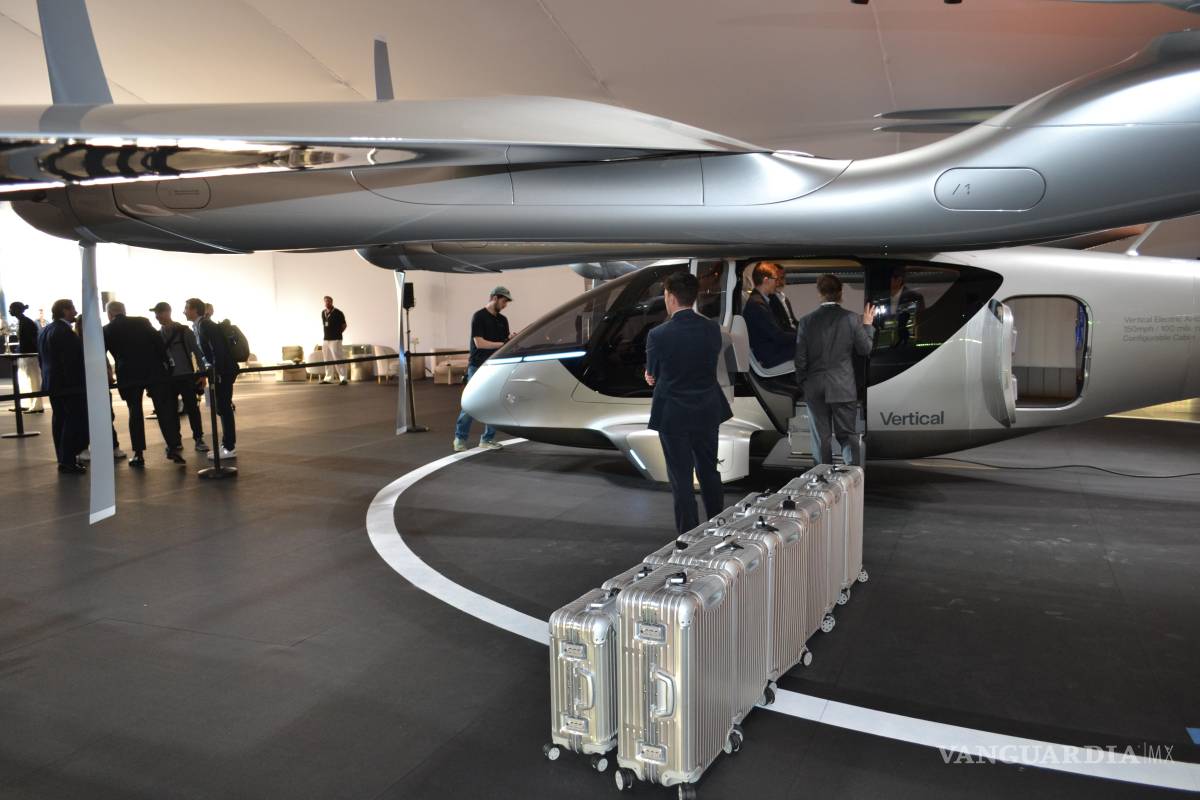 $!Unas personas preparan las maletas frente a un taxi volador eléctrico de la compañía Vertical Aerospace expuesto en Miami Beach, Florida.