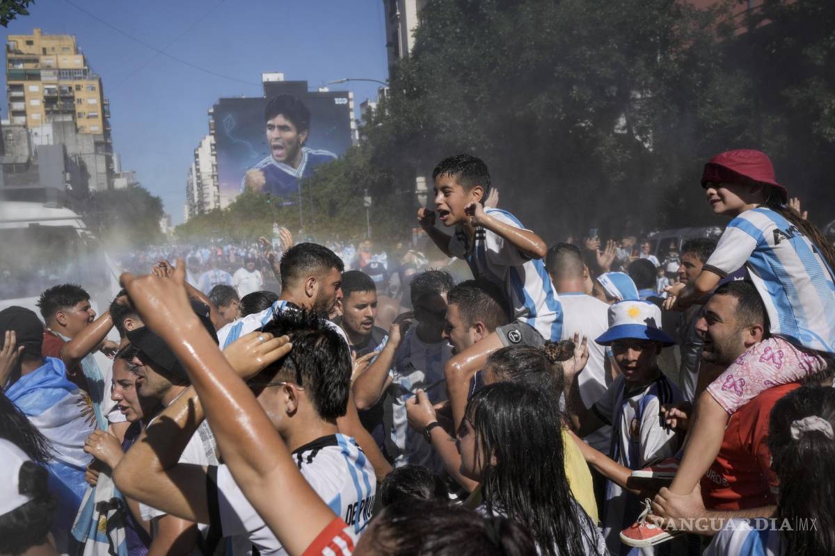 $!Fanáticos del fútbol que esperan para ver a la selección de fútbol de Argentina que ganó la Copa del Mundo son rociados con agua en Buenos Aires, Argentina.