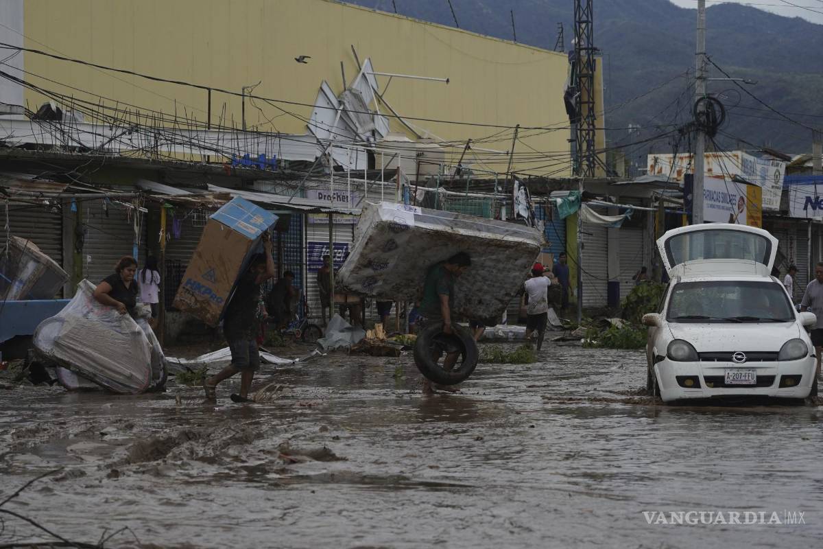 $!La gente camina con bienes saqueados de un centro comercial después de que el huracán Otis arrasara Acapulco, México.