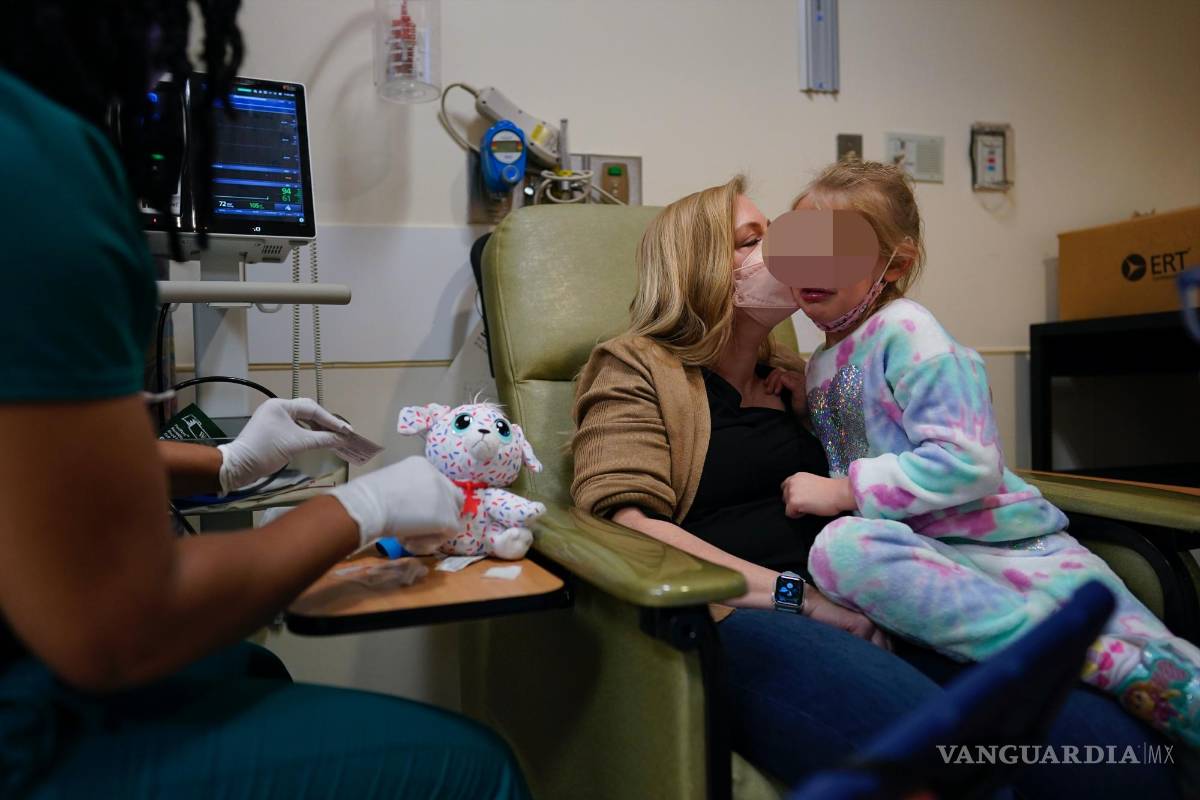 $!Kate Forte besa a su hija Lexie Stroiney, de seis años, mientras la enfermera Michelle Harris usa un peluche para mostrarle cómo le va a sacar sangre.