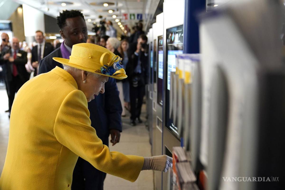 $!La reina Isabel II de Gran Bretaña usa una máquina de tarjetas en la estación de Paddington en Londres.