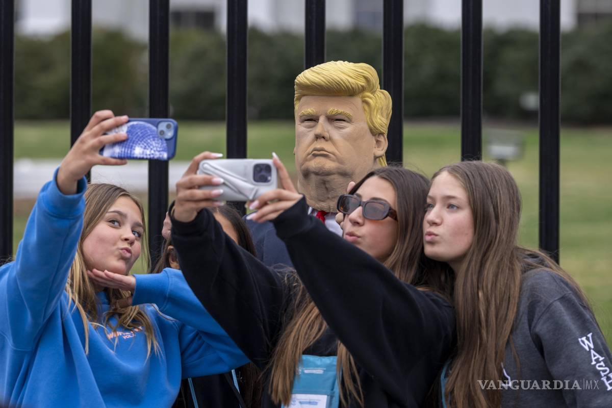 $!Un grupo de jóvenes visitantes posa para una foto con otro visitante de la ciudad que lleva una máscara del presidente Donald Trump frente a la Casa Blanca.
