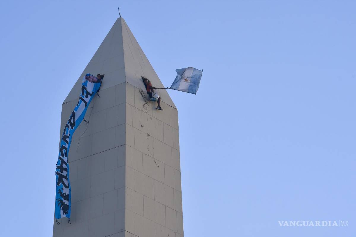$!Hinchas argentinos agitan banderas desde la parte superior del obelisco mientras esperan a la selección de su país, campeona del mundo, en Buenos Aires.