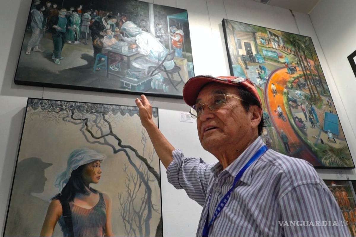 $!Zeng Fanzhi, un arquitecto jubilado convertido en artista, señala una de sus pinturas que retrata una prueba de COVID en su estudio en Shenzhen, en China.