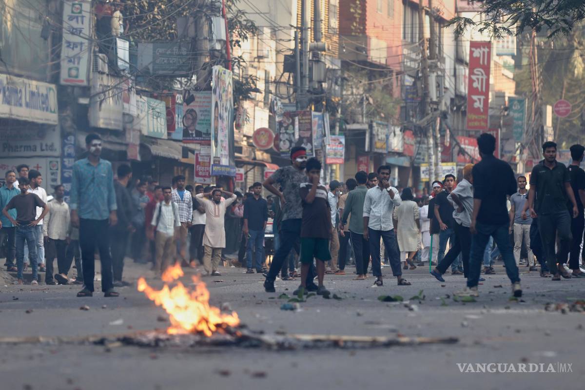 $!Manifestantesse enfrentan con la policía frente a la residencia demolida del padre de la derrocada primera ministra Sheikh Hasina tras el veredicto en su contra.