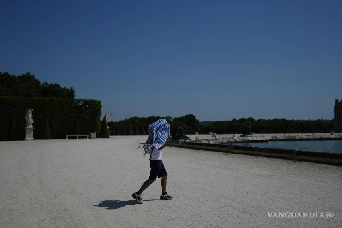 $!Un hombre se protege del sol con un pañuelo mientras camina por el jardín del Palacio de Versalles, a las afueras de París.