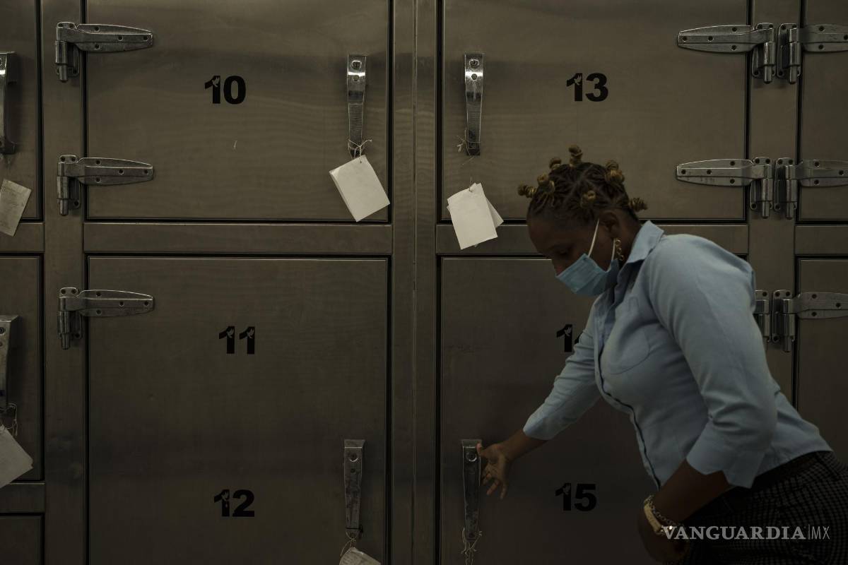 $!Una técnica forense abre la puerta de una cámara frigorífica donde se guardan los restos mortales de los migrantes que iban a bordo de un cayuco mauritano.