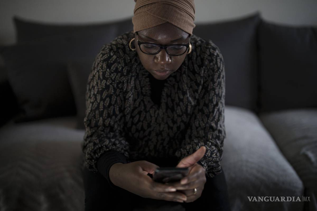 $!May Sow, cuyo sobrino Alassane Sow desapareció tras embarcar en un cayuco en Mauritania, mira su celular en su casa en Orleans, Francia.