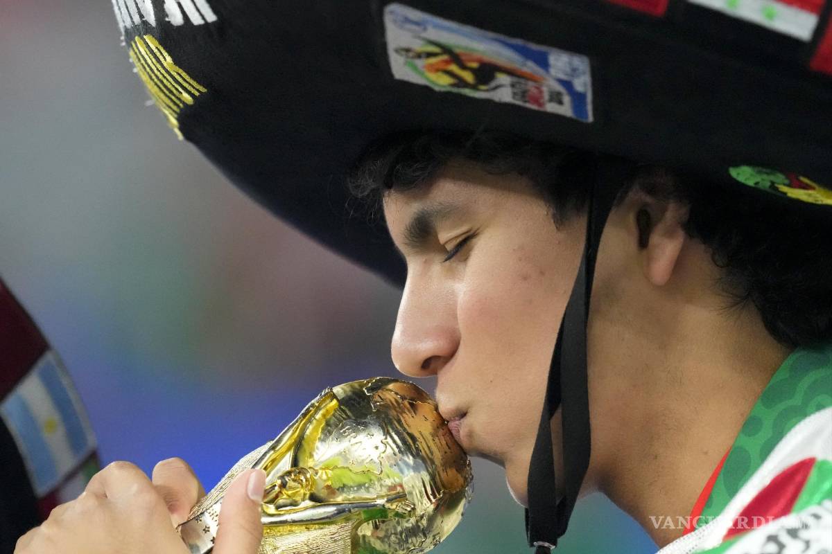 $!Un hincha del equipo de México besa una copia del trofeo de la Copa Mundial durante los calentamientos previos al partido entre México y Polonia.