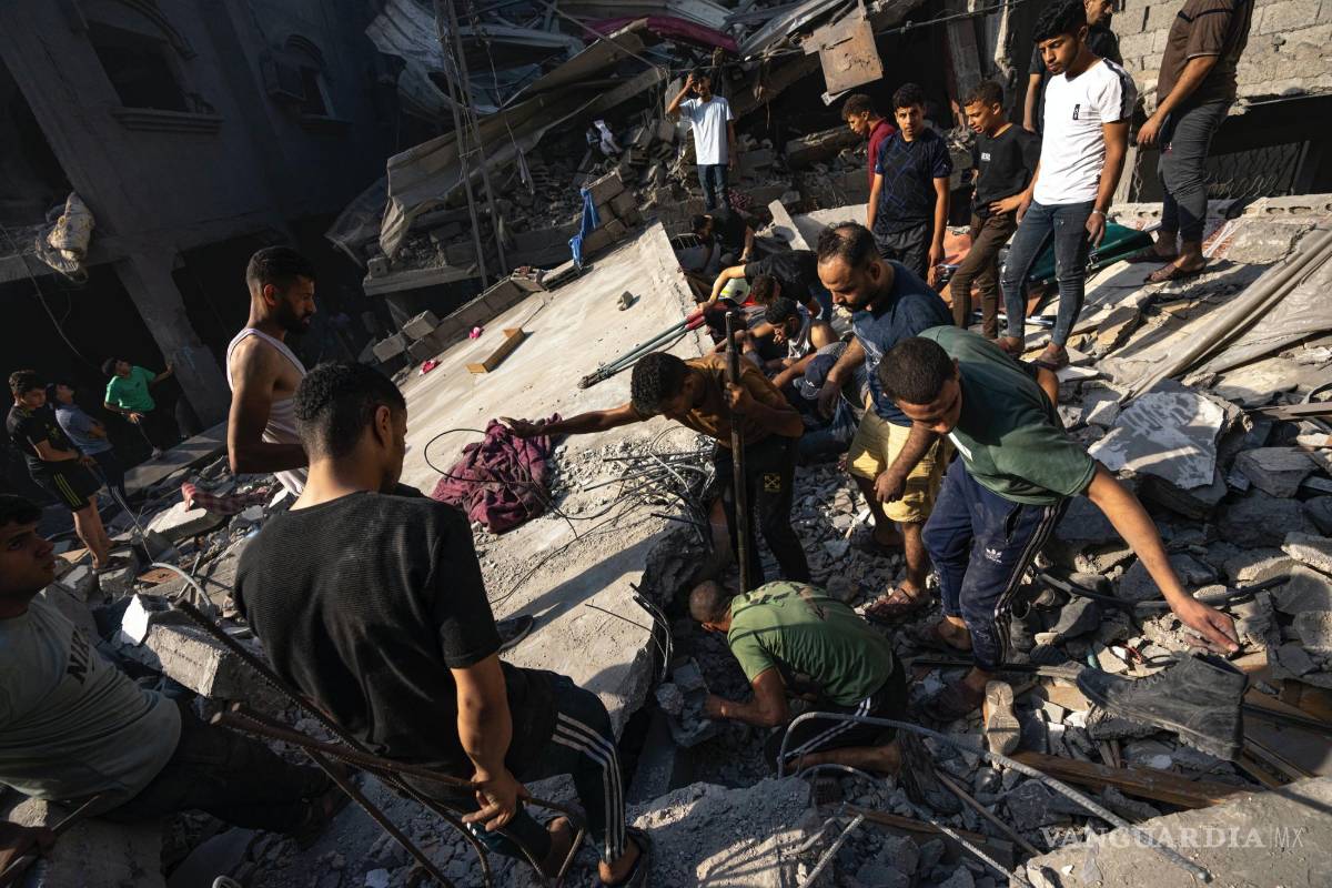 $!Palestinos buscan cadáveres y sobrevivientes entre los restos de un edificio residencial arrasado tras un ataque aéreo israelí sobre el campo de refugiados.