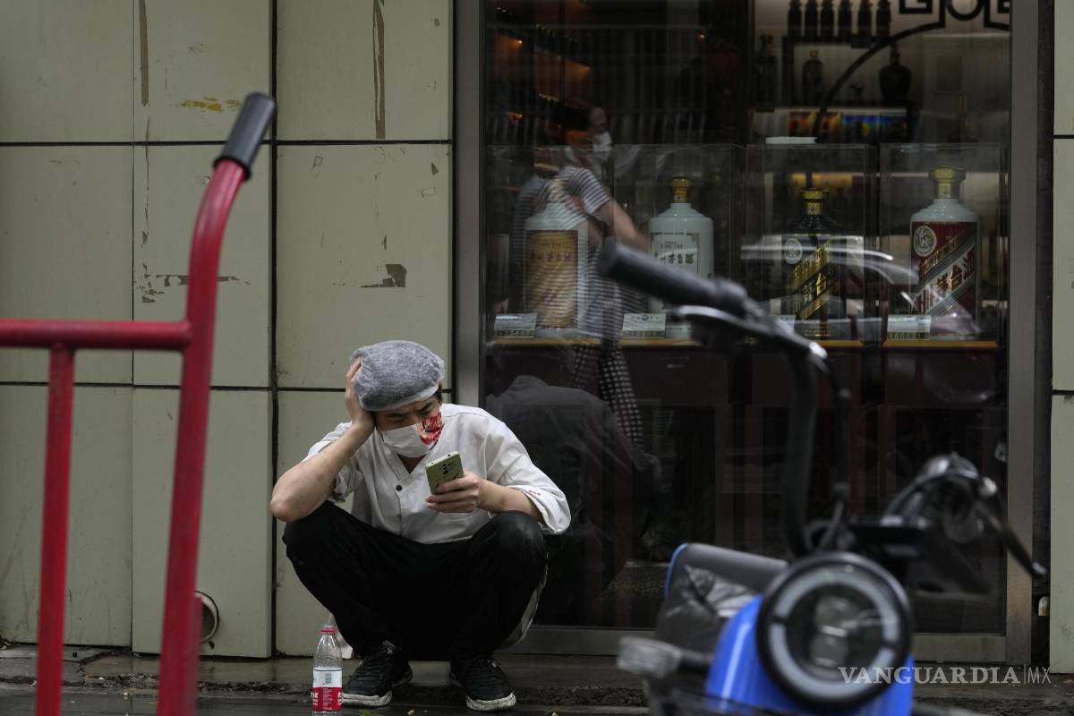 $!El cocinero de un restaurante con una máscara toma un descanso en la acera en Beijing, China