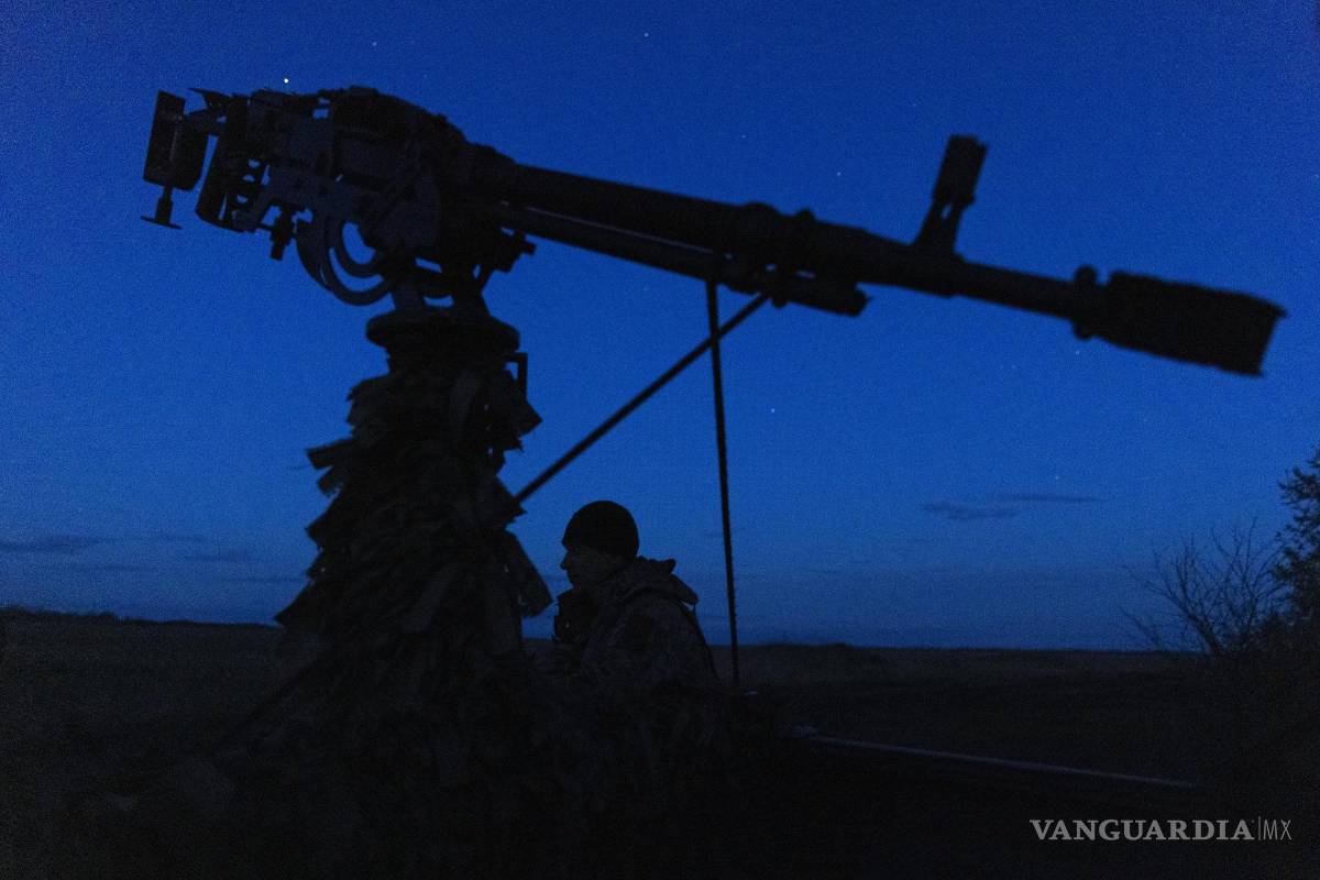 $!Un soldado parado cerca de un sistema de armas montado en una camioneta durante una patrulla nocturna, en busca de drones rusos.