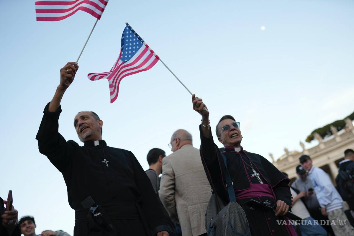 $!Clérigos ondean banderas de Estados Unidos durante el discurso del recién elegido Papa León XIV en el Vaticano.
