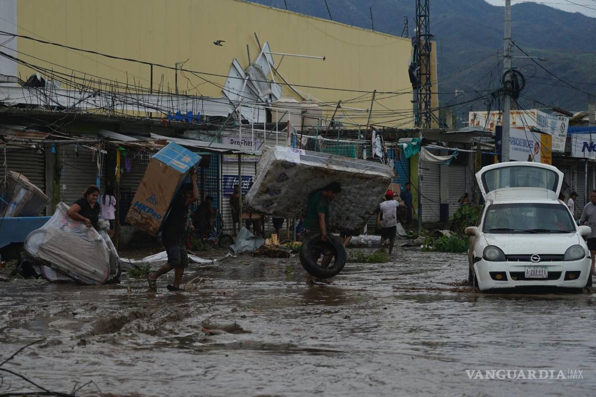 $!La gente camina con bienes saqueados de un centro comercial después de que el huracán Otis arrasara Acapulco, Guerrero (México).