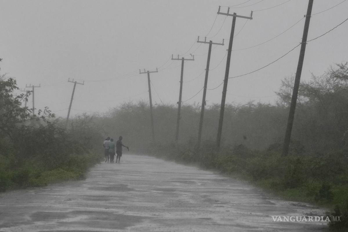 $!Personas caminan por una carretera durante el paso del huracán Melissa en Rocky Point, Jamaica.
