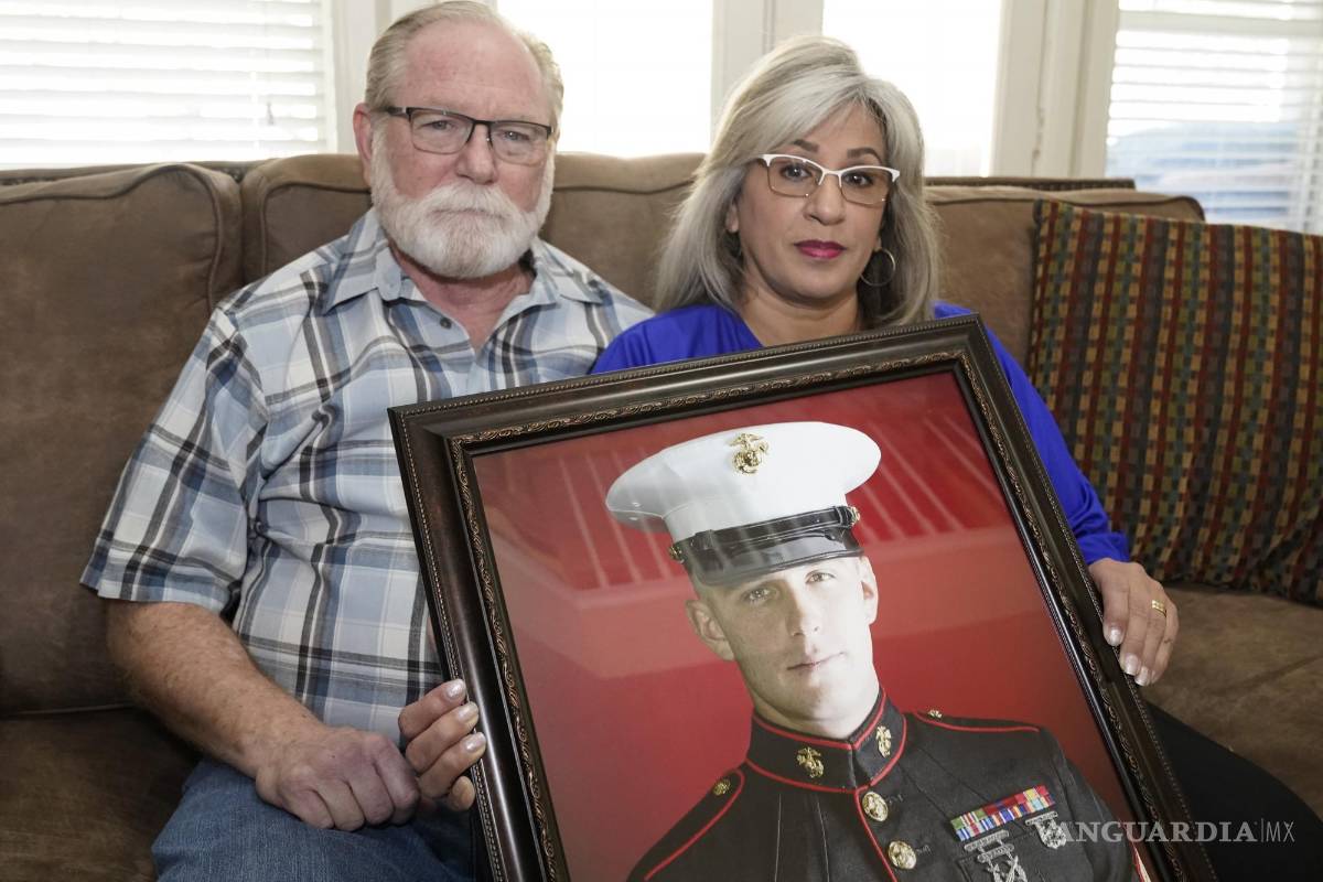 $!Joey y Paula Reed posan para una foto con un retrato de su hijo Trevor Reed, veterano de la Marina y prisionero ruso, en su casa de Fort Worth, Texas.