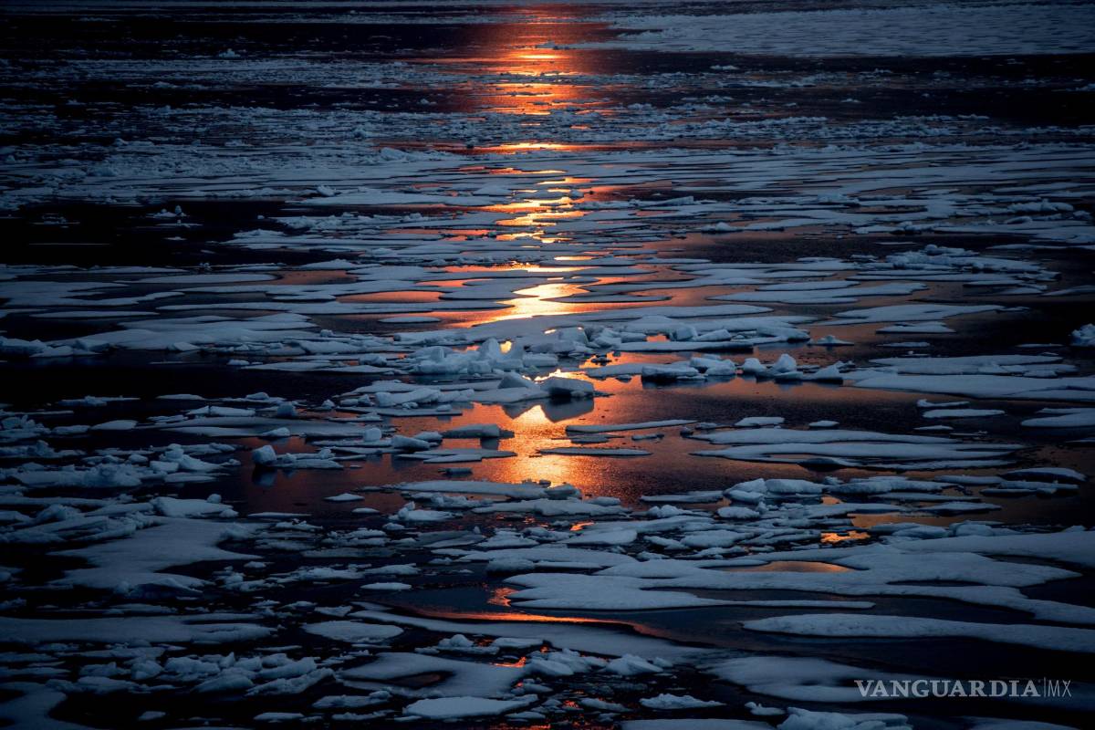 $!El sol de medianoche brilla a través del hielo marino a lo largo del Pasaje del Noroeste en el archipiélago ártico canadiense, el domingo 23 de julio de 2017. Cuando está cubierto de nieve y hielo, el Ártico refleja la luz solar y el calor. Pero esa manta está menguando. Y a medida que se derrite más hielo marino en el verano, “estás revelando superficies oceánicas realmente oscuras, como una camiseta negra”, dice la científica del hielo Twila Moon. Como la ropa oscura, los parches abiertos del mar absorben el calor del sol más fácilmente. AP/David Goldman