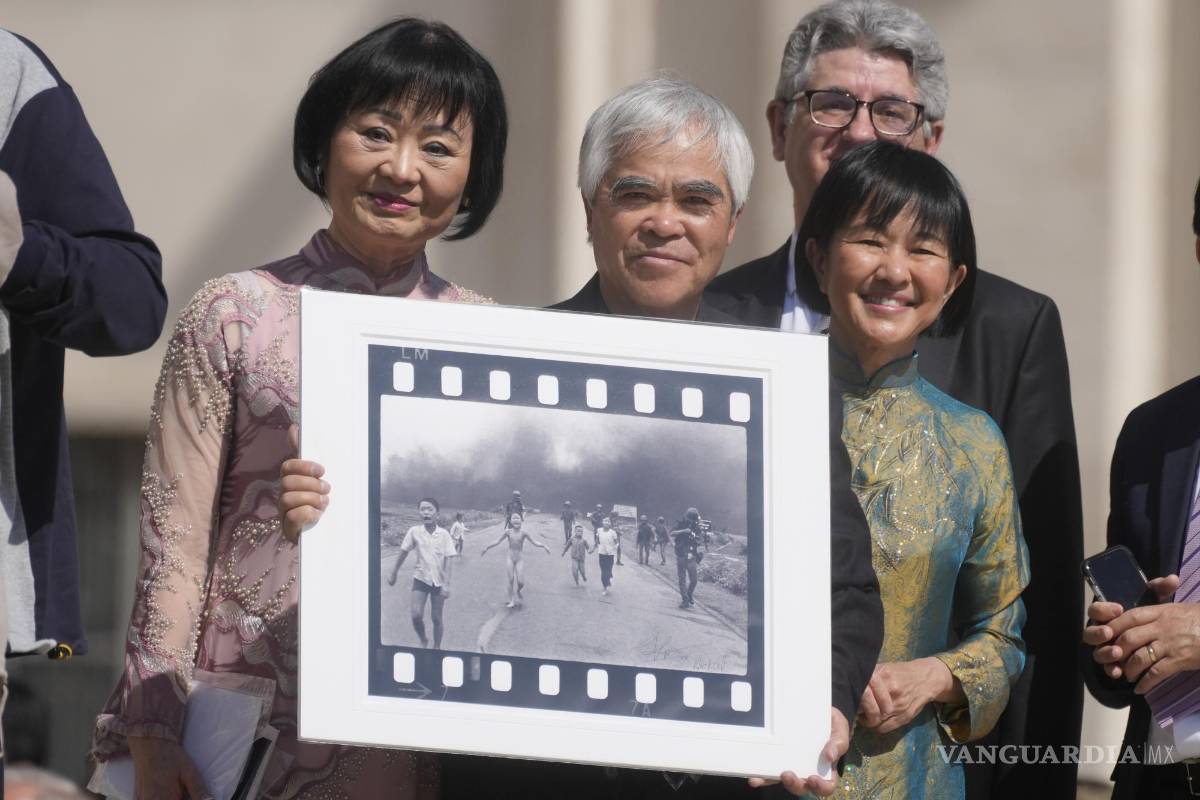 $!El fotógrafo ganador del Premio Pulitzer Nick Ut (c), flanqueado por Kim Phuc (i) sostiene la “Niña del napalm” en la Plaza de San Pedro en el Vaticano.