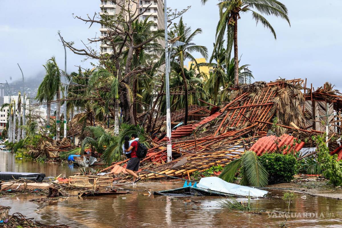 $!Un hombre sostiene a una niña mientras camina por una calle afectada por el paso del huracán Otis en el balneario de Acapulco, en el estado de Guerrero, México.